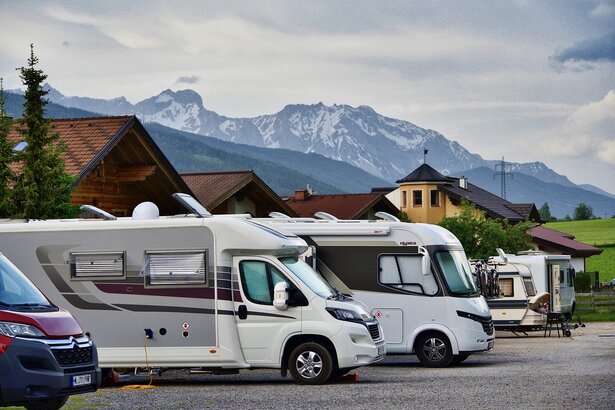 Mehrere verschiedene Wohnmobil-Typen nebeneinander auf einem Parkplatz